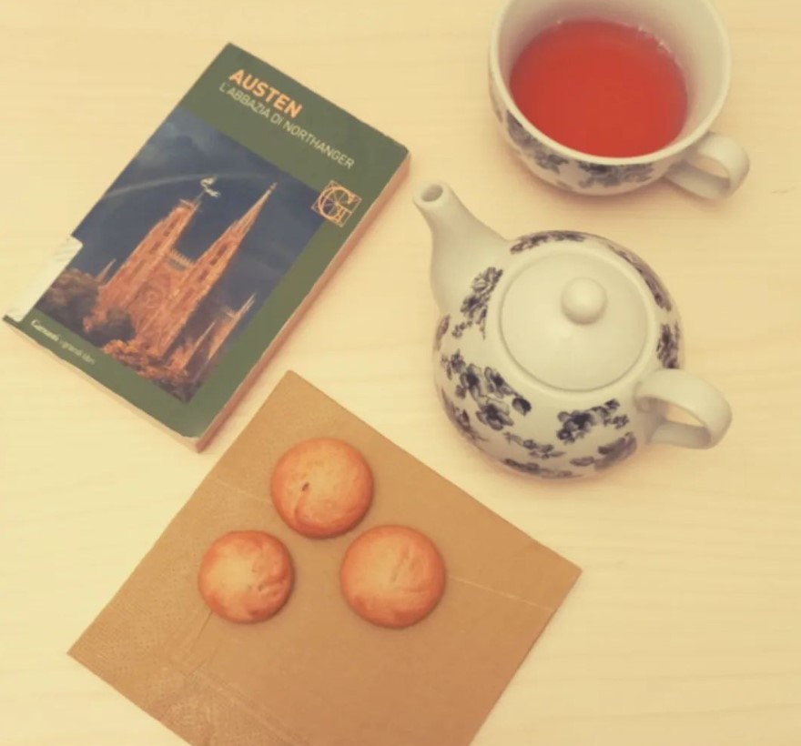 Libro "L'abbazia di Northanger" con tè caldo, teiera e biscotti